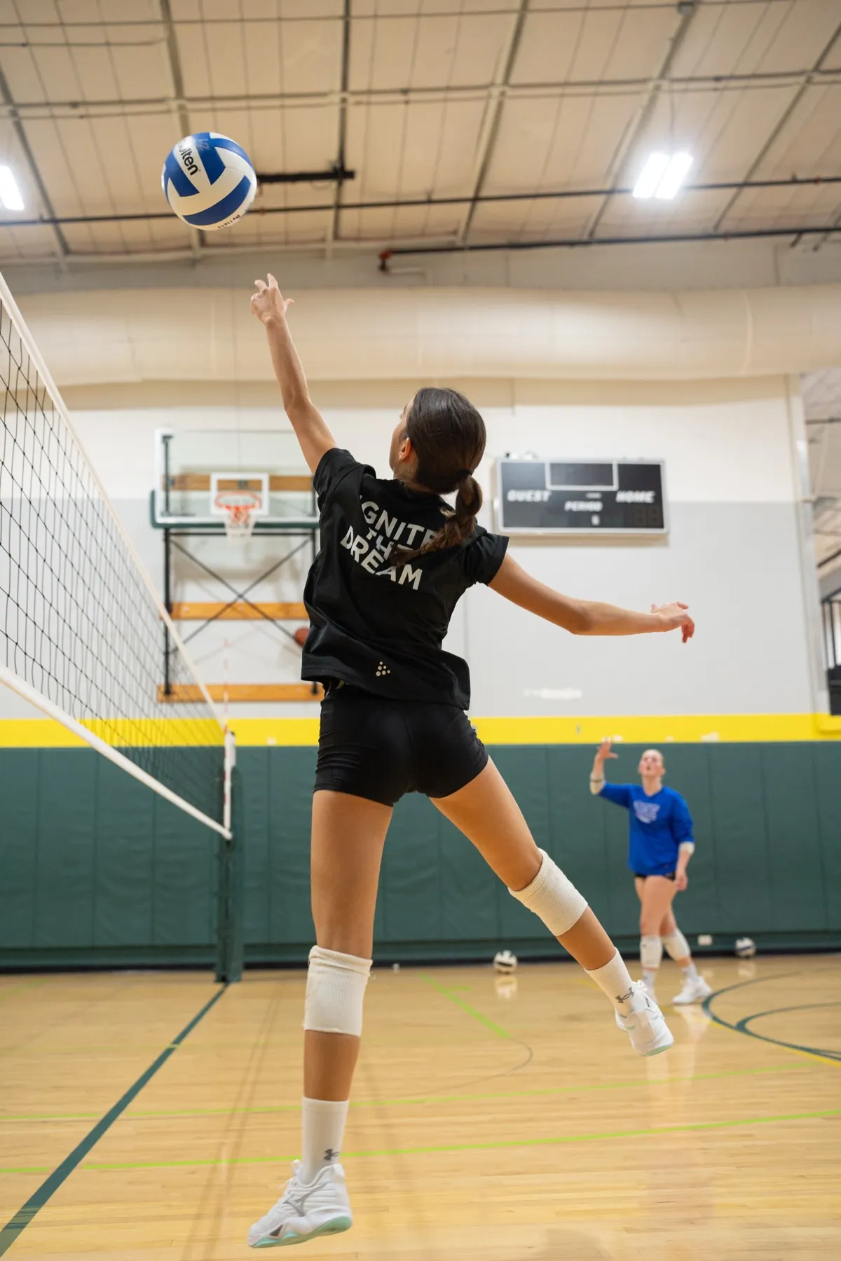 Female player leaping to spike during indoor volleyball practice
